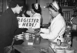 A una mujer le recortan los cupones de la cartilla de racionamiento después de recibir su azúcar y su mantequilla para la semana durante la Segunda Guerra Mundial