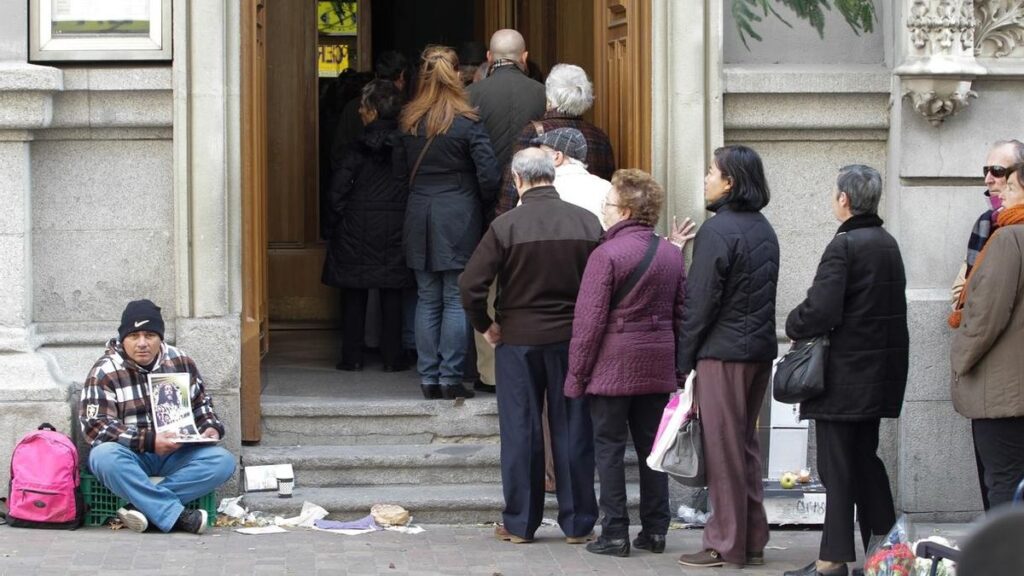 Personas pidiendo en la puerta de Cáritas